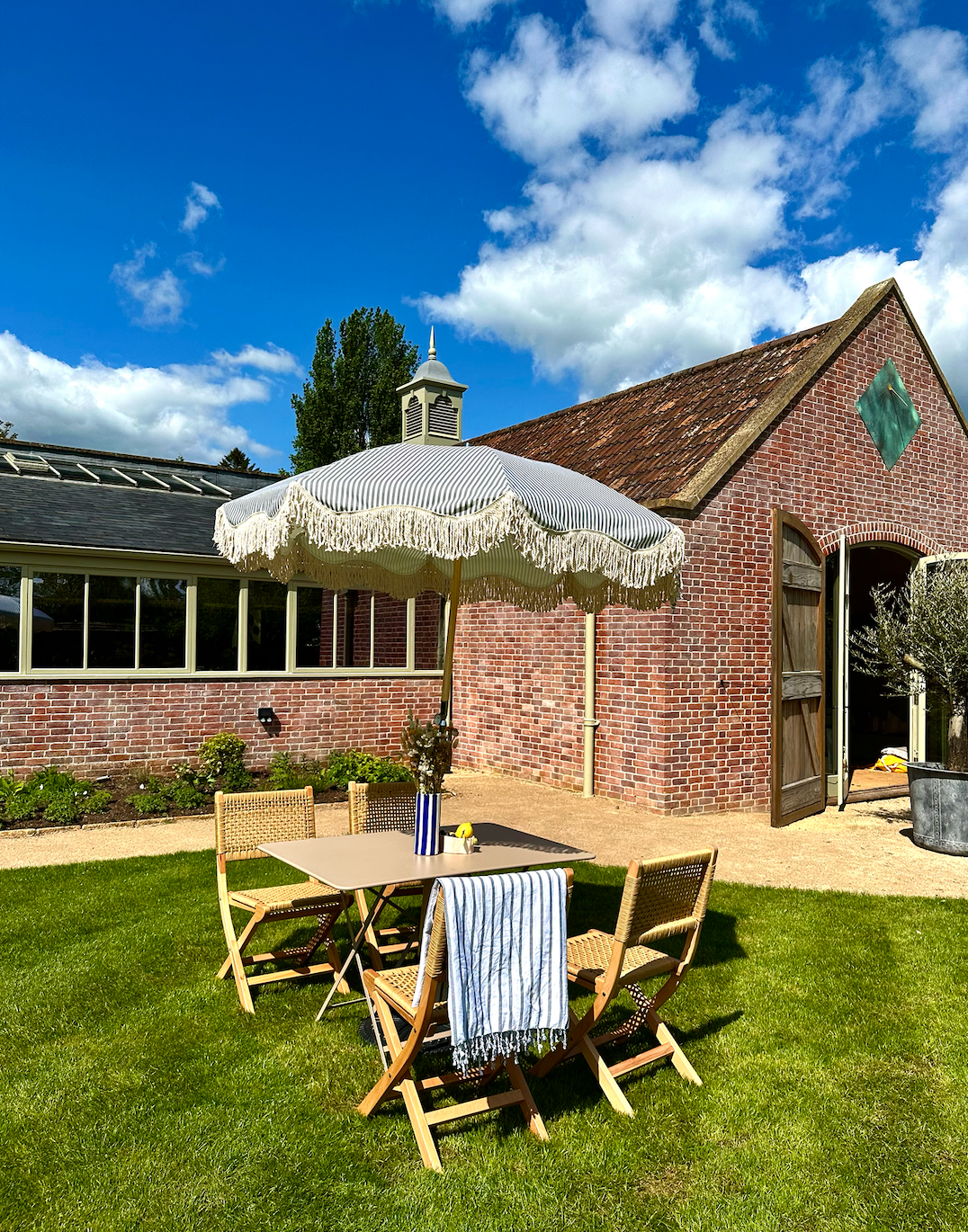 The Betty timeless chic parasol with natural cotton fringing, wooden frame pole, adjustable positioning, collapsible design, and matching canvas carry bag. Beach umbrella. Garden umbrella.