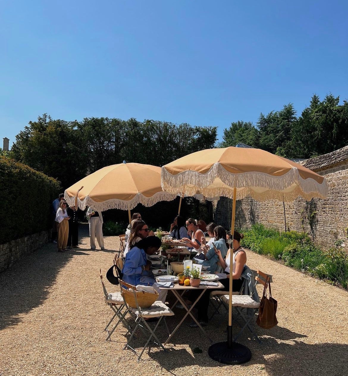 The Brenda timeless chic parasol with natural cotton fringing, adjustable wooden frame pole, collapsible design, and matching canvas carry bag.