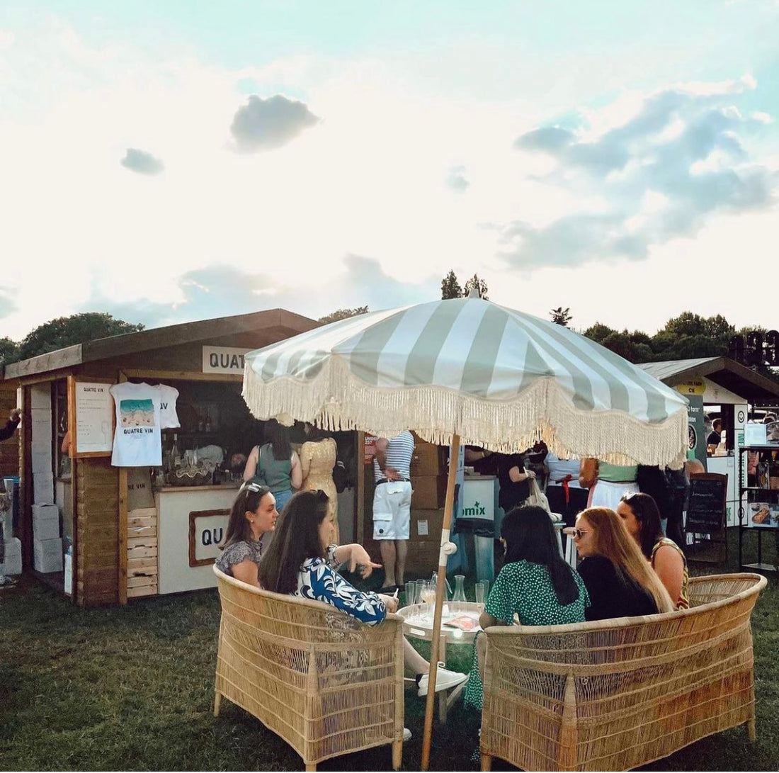 The Clara pastel green and white striped parasol with natural cotton fringing, adjustable wooden frame pole, collapsible design, and matching canvas carry bag.