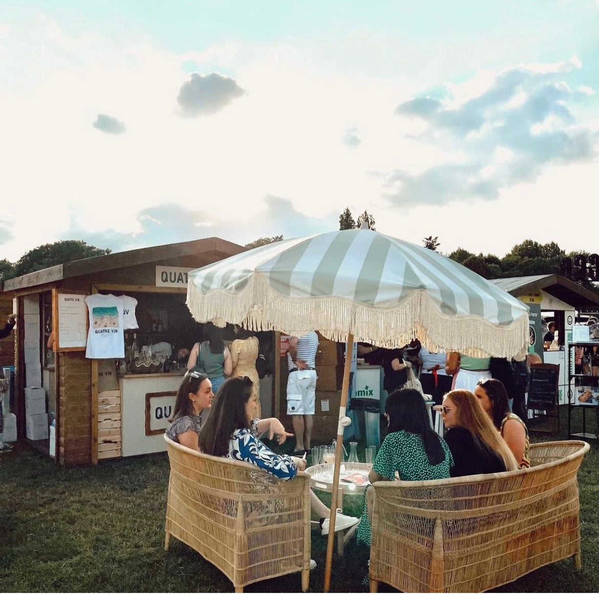 The Clara pastel green and white striped parasol with natural cotton fringing, adjustable wooden frame pole, collapsible design, and matching canvas carry bag.