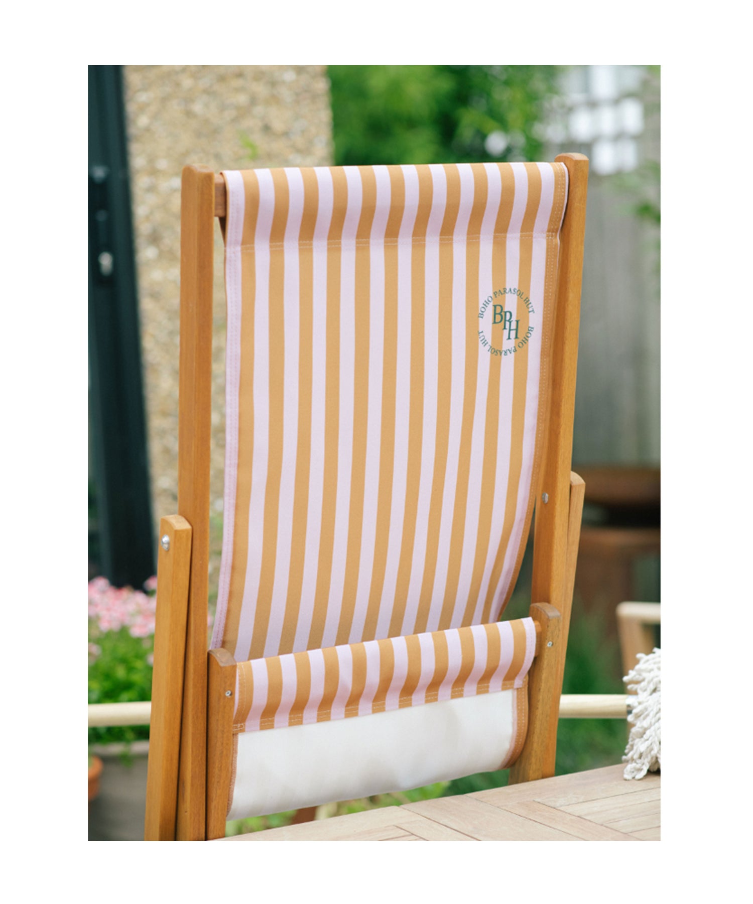 Pink and brown striped deckchair featuring The Gigi parasol, perfect for a chic outdoor seating setup with a touch of elegance.