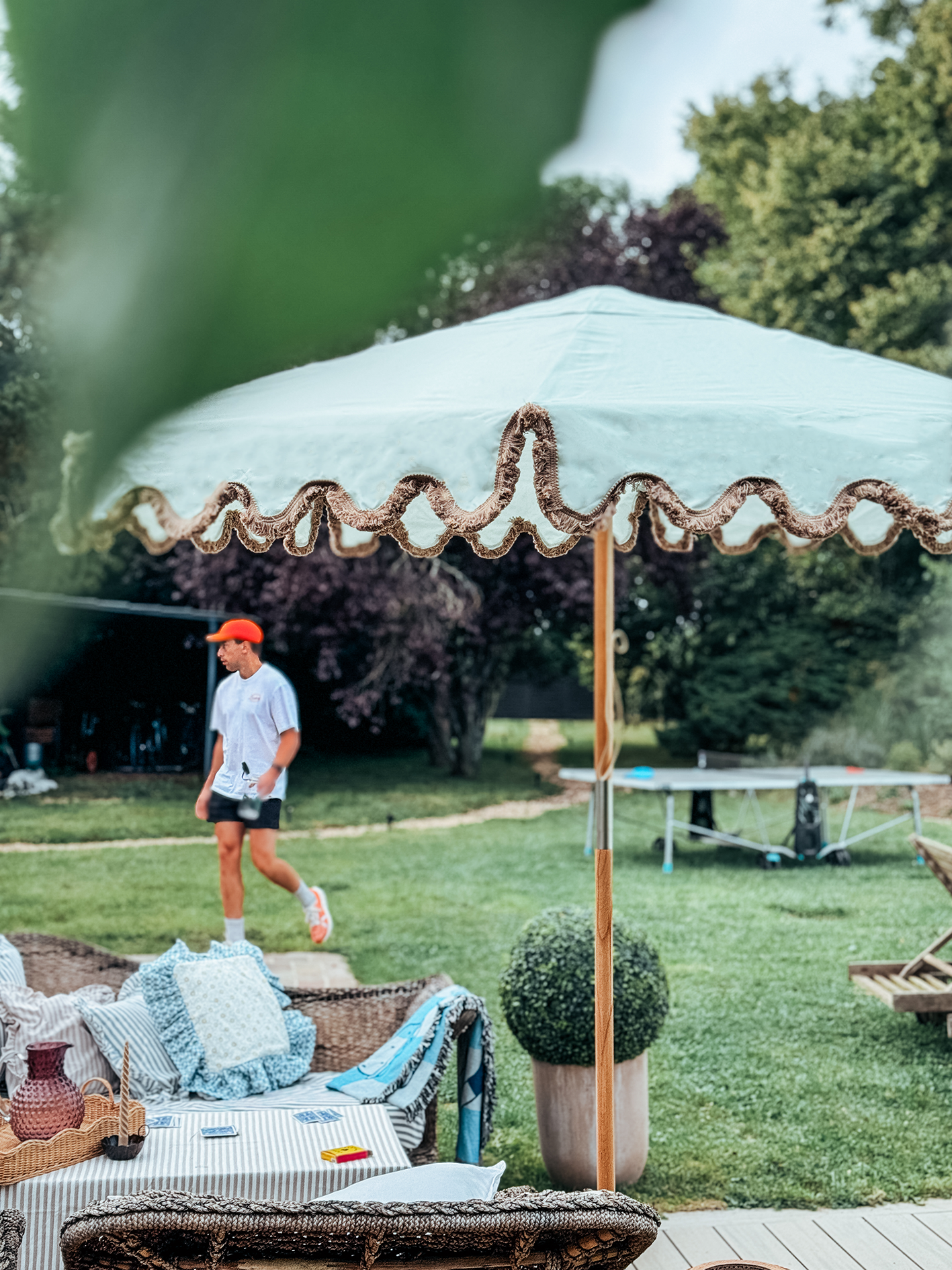 Willow sage green parasol with brown fringed wavy edge and wooden frame. Patio tablescape umbrella.