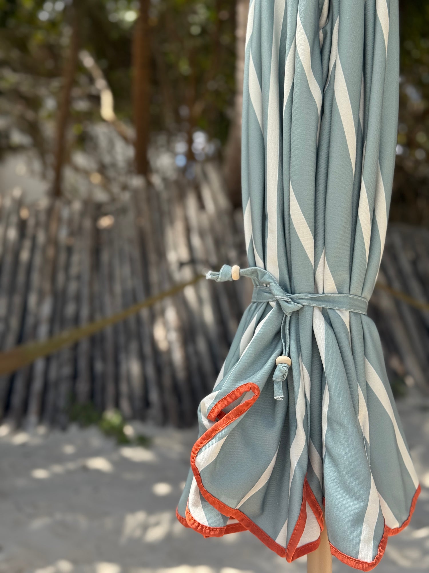 Freddie sage green and white striped parasol with orange-taped scallop edge and beech wood frame