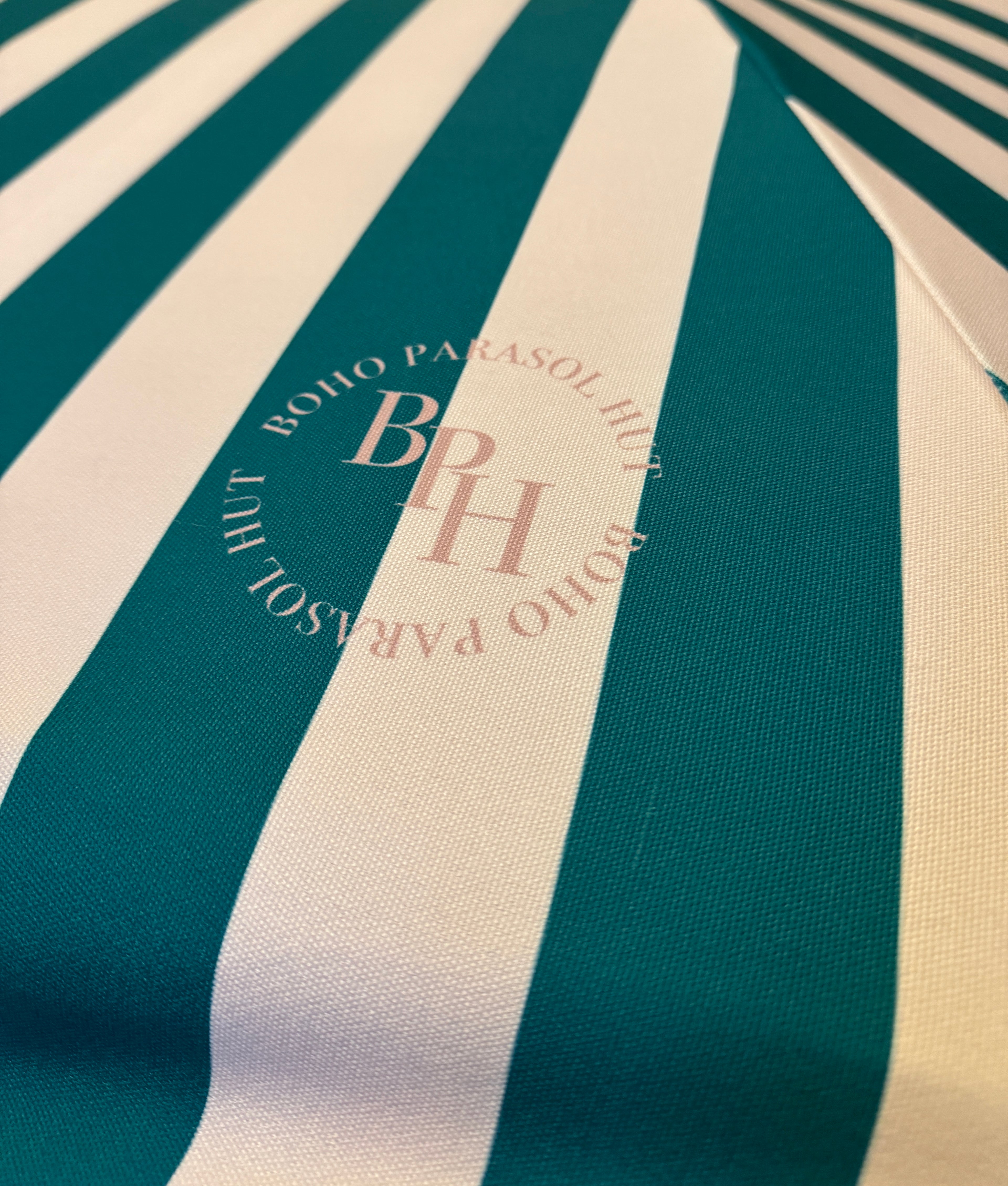 Polly parasol with pink and green stripes, dreamy ruffle edging, wooden frame, adjustable positioning, collapsible design, and matching canvas carry bag.