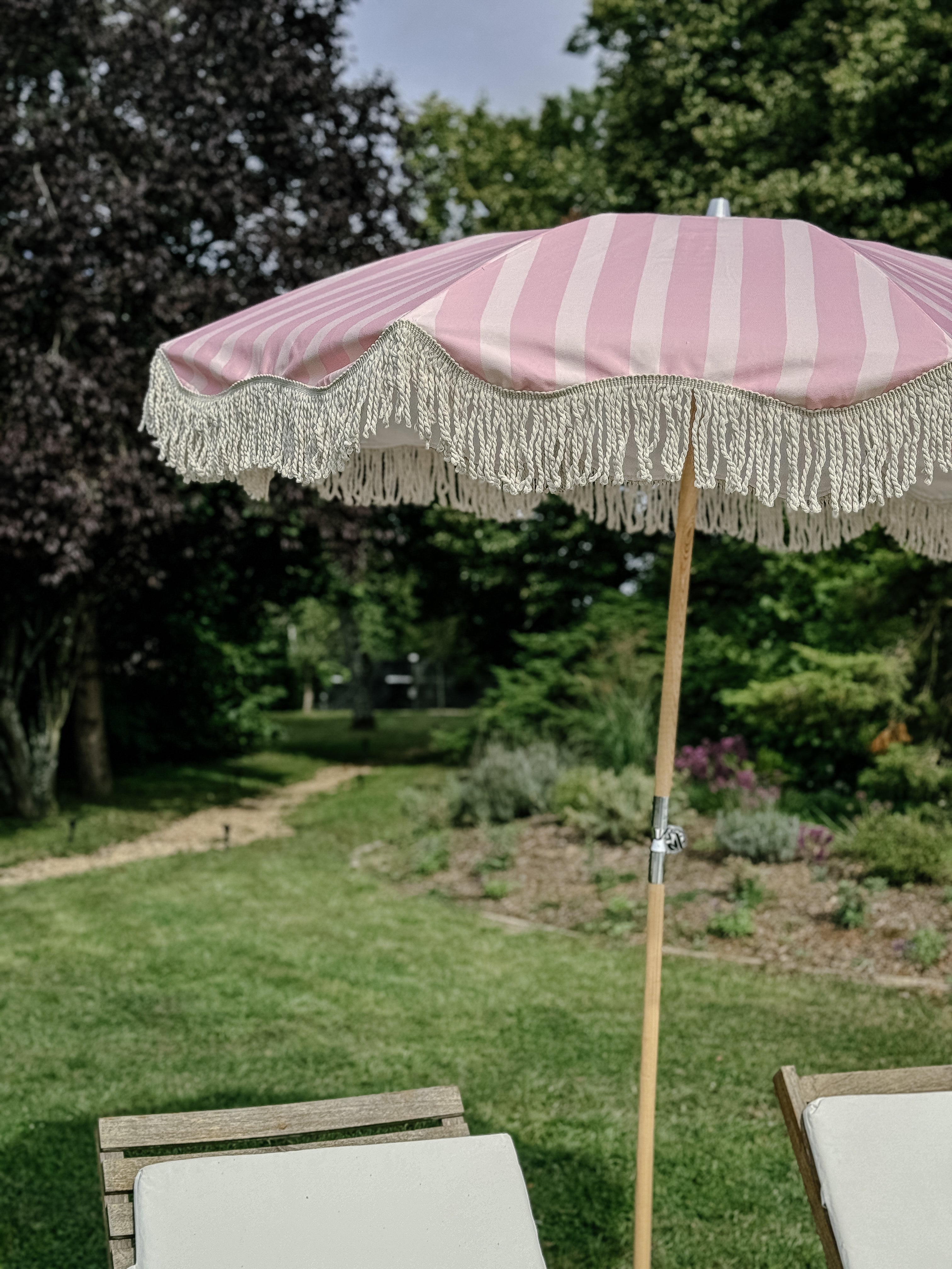 Pink on pink striped parasol with natural cotton fringing, featuring an authentic wooden frame and adjustable positioning, perfect for gardens, patios, and outdoor events