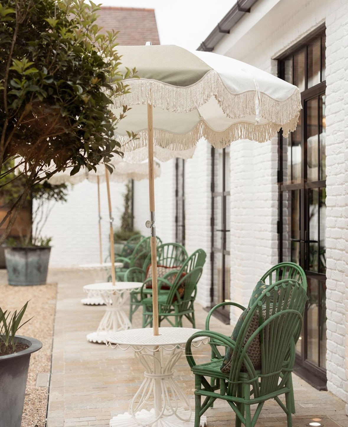 The Salma timeless chic parasol with natural cotton fringing, wooden frame pole, adjustable positioning, collapsible design, and matching canvas carry bag. Patio umbrella.