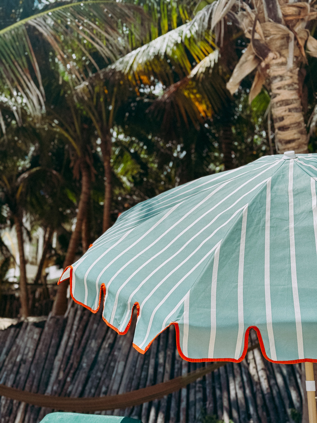 Freddie sage green and white striped parasol with orange-taped scallop edge and beech wood frame