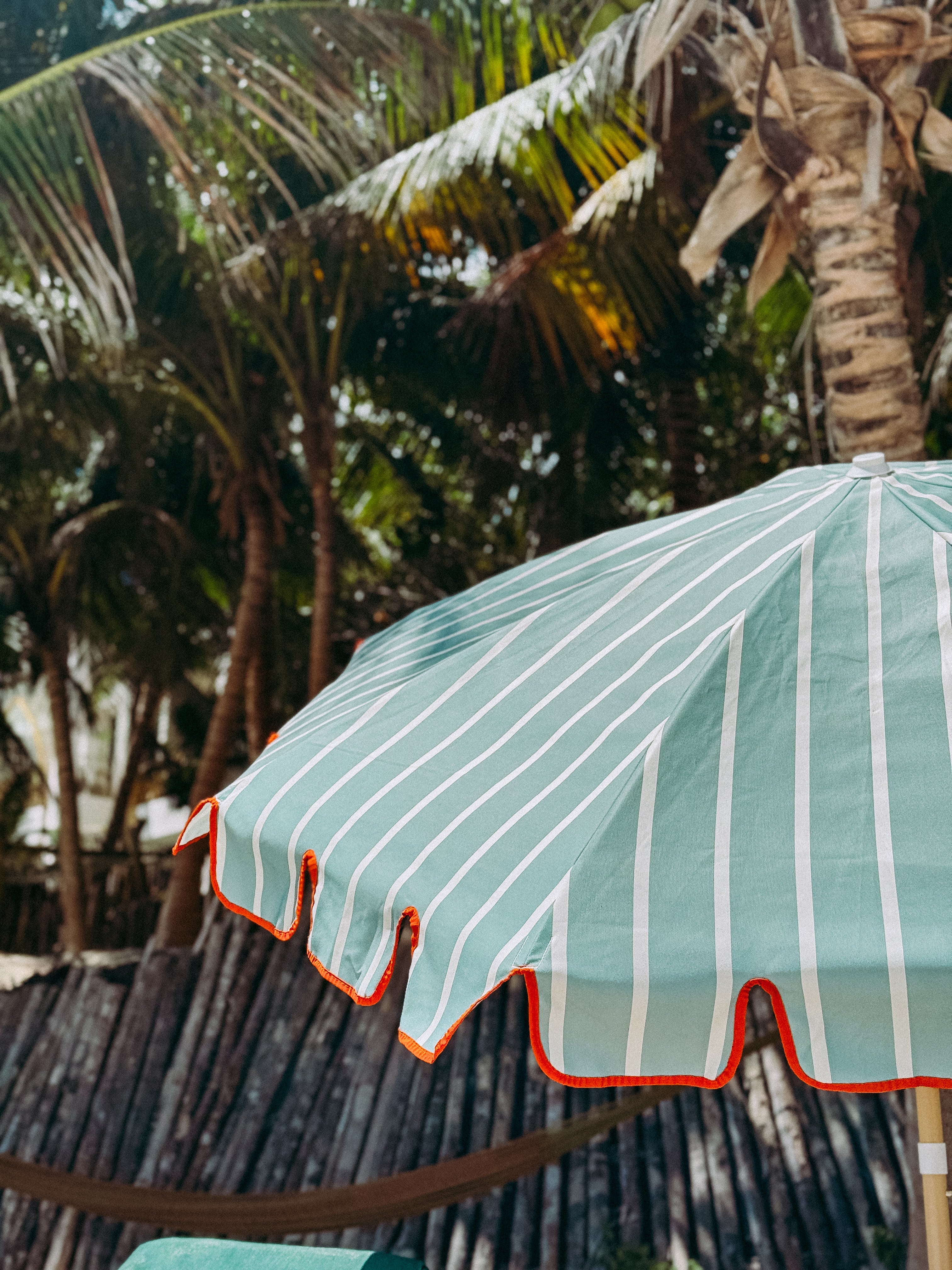 Sage green striped parasol with scalloped edging, designed for stylish outdoor living