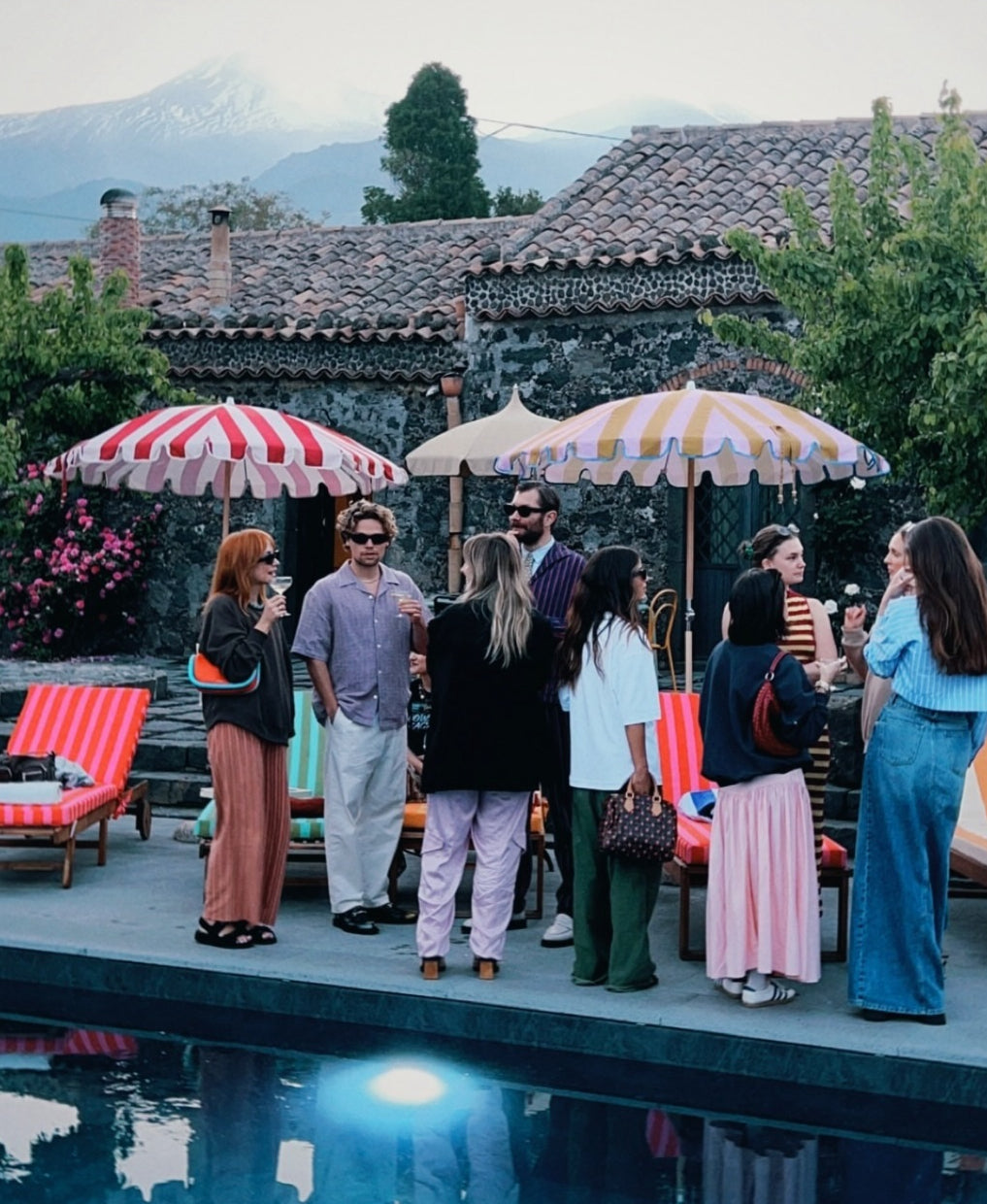 Agnes parasol with nude pink and red stripes, scallop edging, pastel pink trim, wooden frame, adjustable positioning, collapsible design, and matching canvas carry bag.