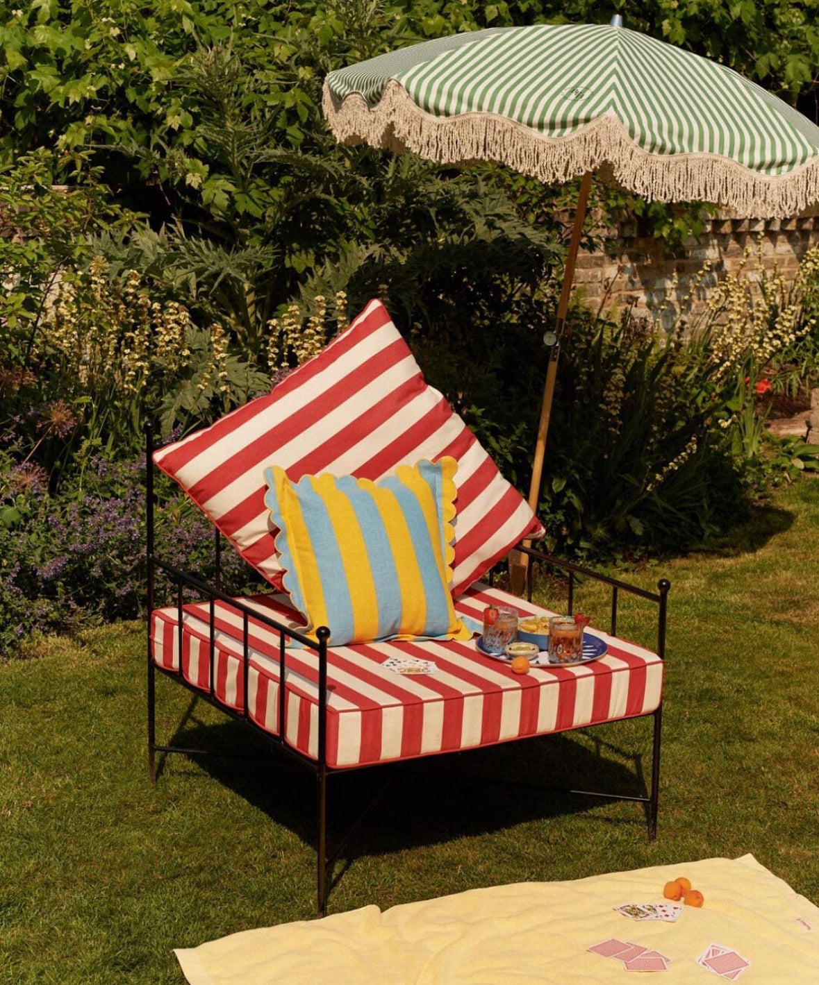 The Theodore luxury parasol with natural cotton fringing, wooden frame pole, adjustable positioning, collapsible design, and matching canvas carry bag.