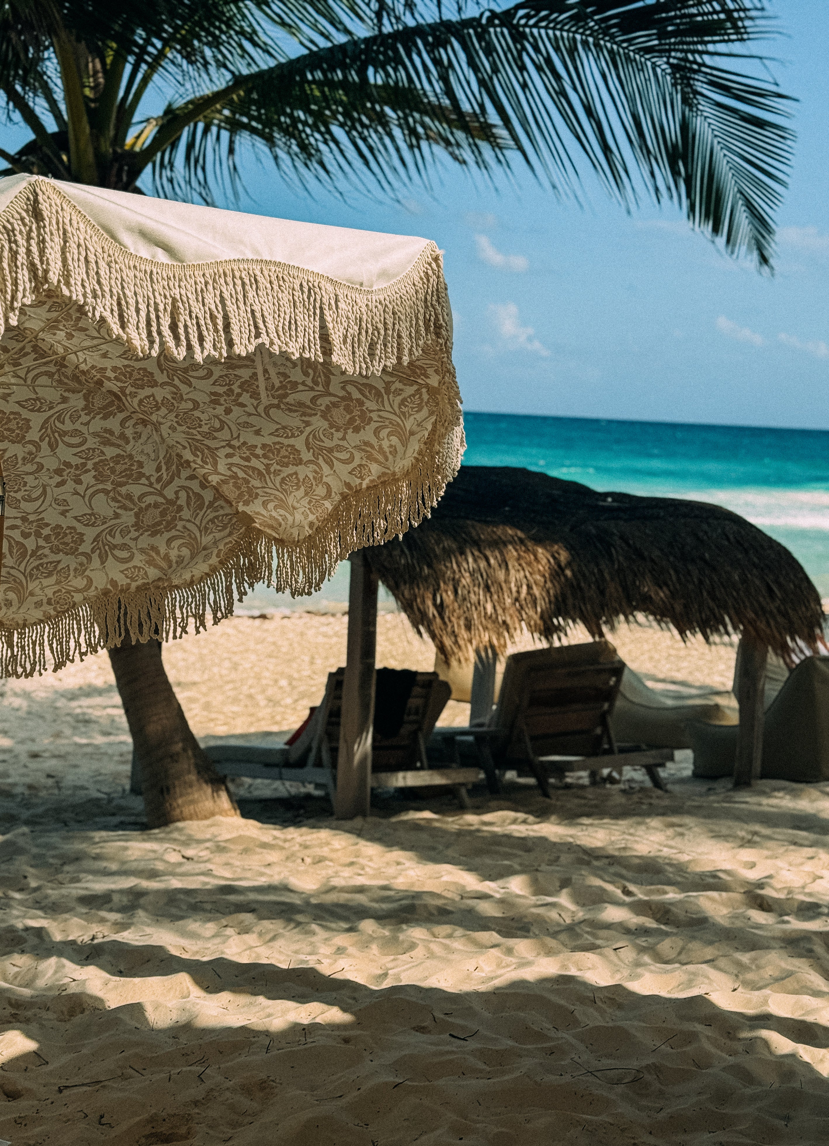 Elegant Cynthia cream parasol with floral interior design, set up on a sunny beach, offering shade and style for beachgoers
