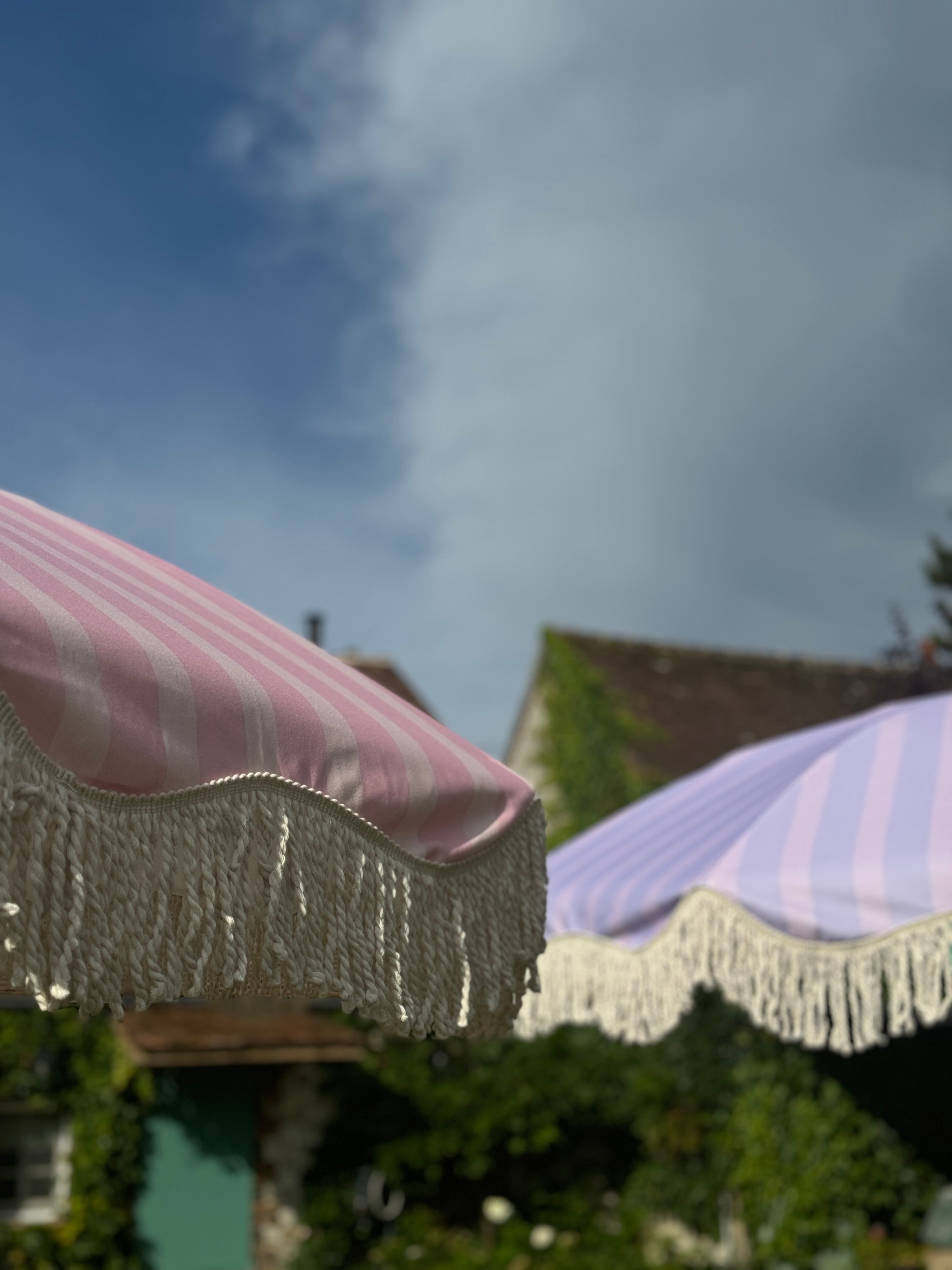 Lilac striped parasol with natural cotton fringing, featuring an authentic wooden frame and adjustable positioning, perfect for gardens, patios, and outdoor events.