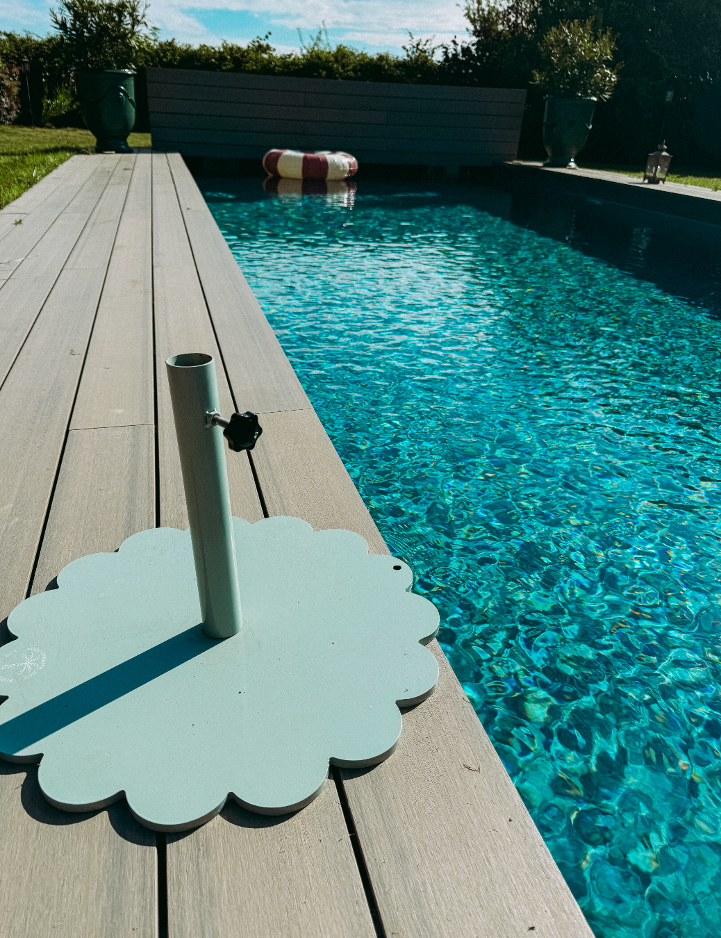 Elegant scallop parasol base supporting a parasol at a poolside, adding style and stability to outdoor relaxation space