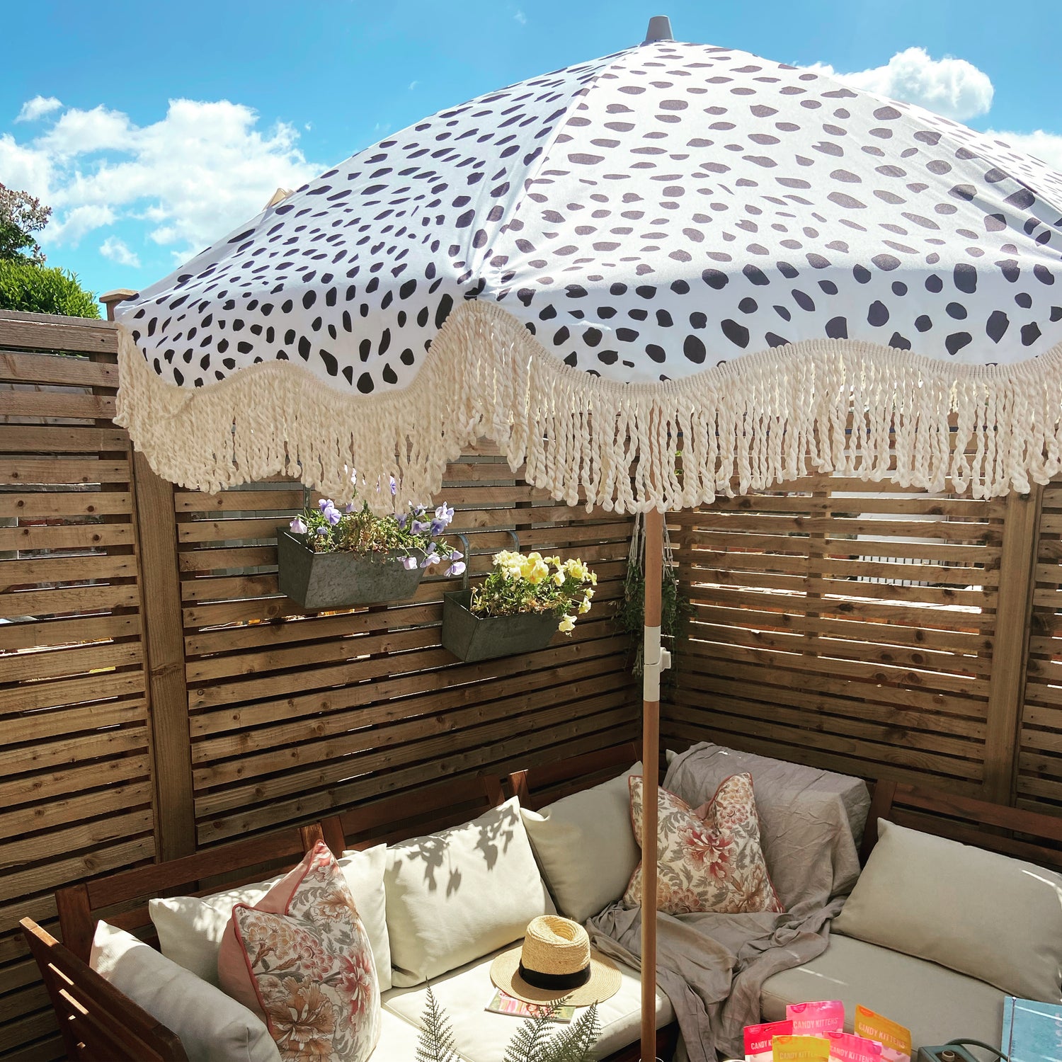 The Margot boho chic parasol featuring pastel blue with black dalmatian print, natural cotton fringing, adjustable wooden frame pole, collapsible design, and matching canvas carry bag.