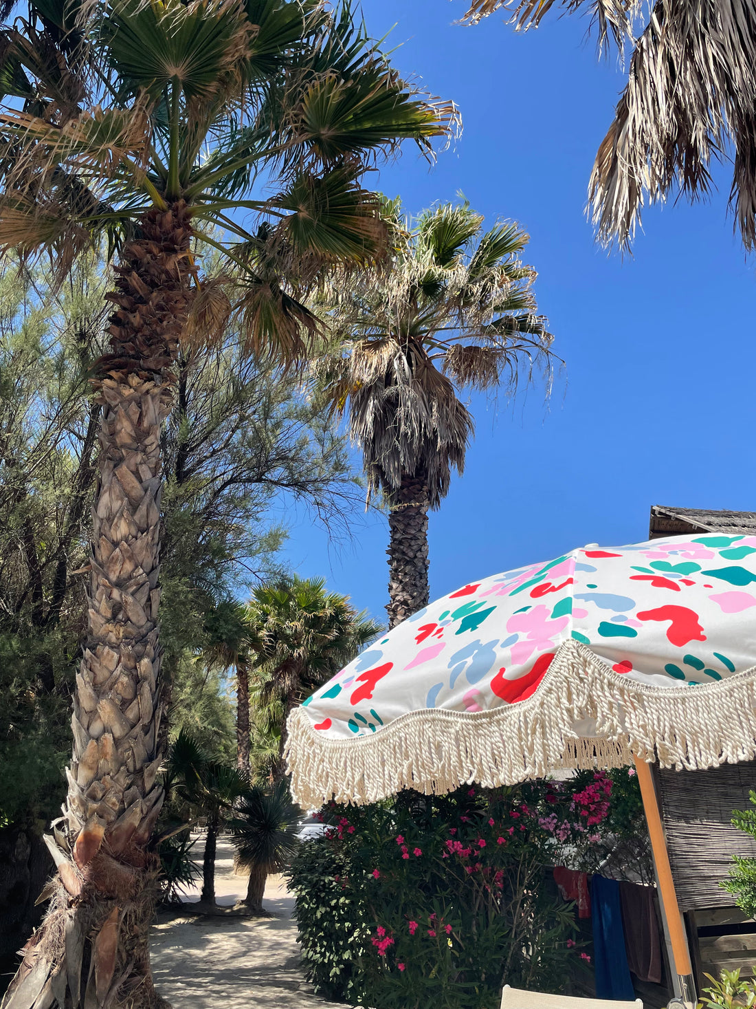 The Florence boho chic parasol with vibrant floral pattern, natural cotton fringing, adjustable wooden frame pole, collapsible design, and matching canvas carry bag.