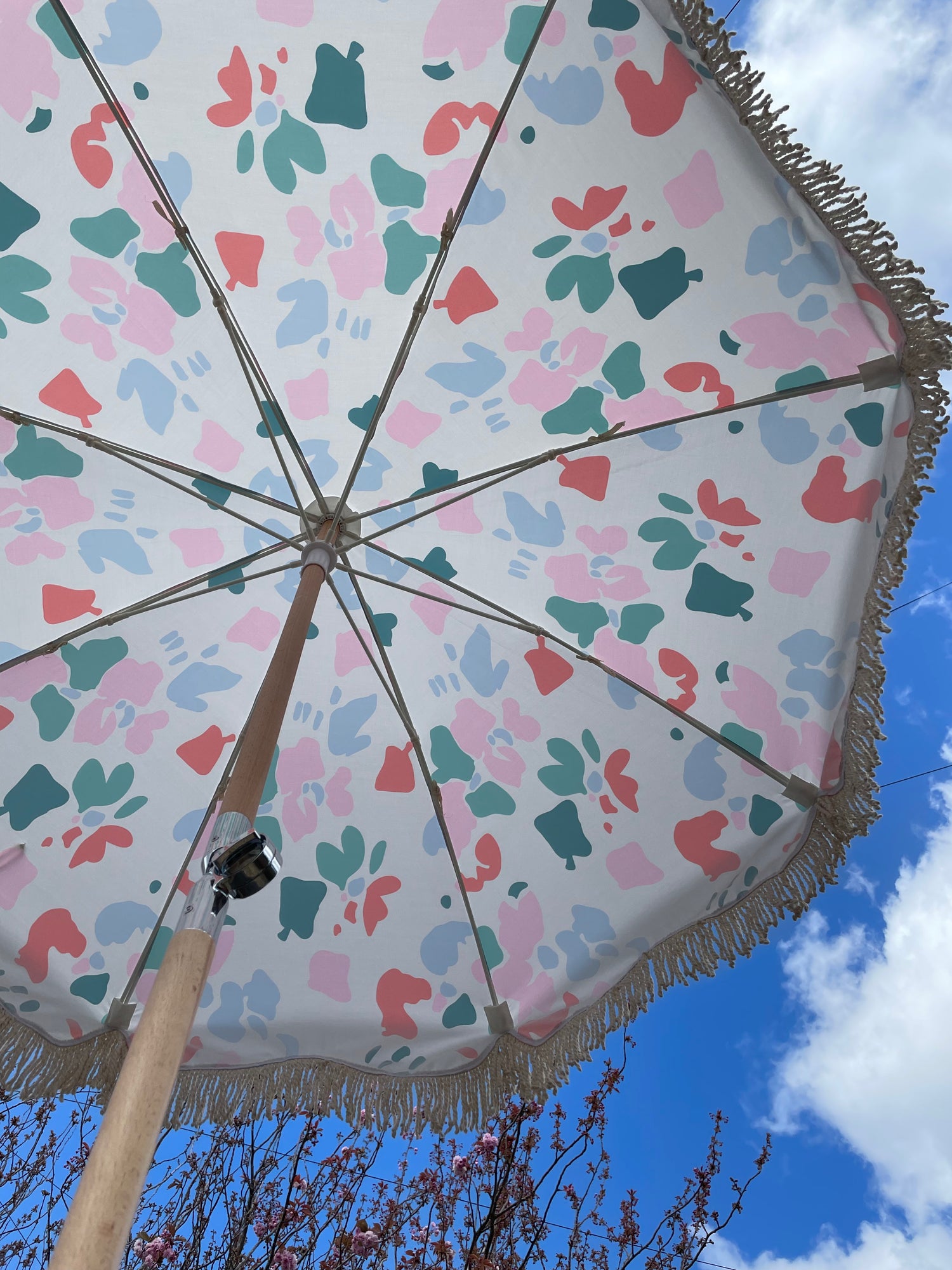 The Florence boho chic parasol with vibrant floral pattern, natural cotton fringing, adjustable wooden frame pole, collapsible design, and matching canvas carry bag.
