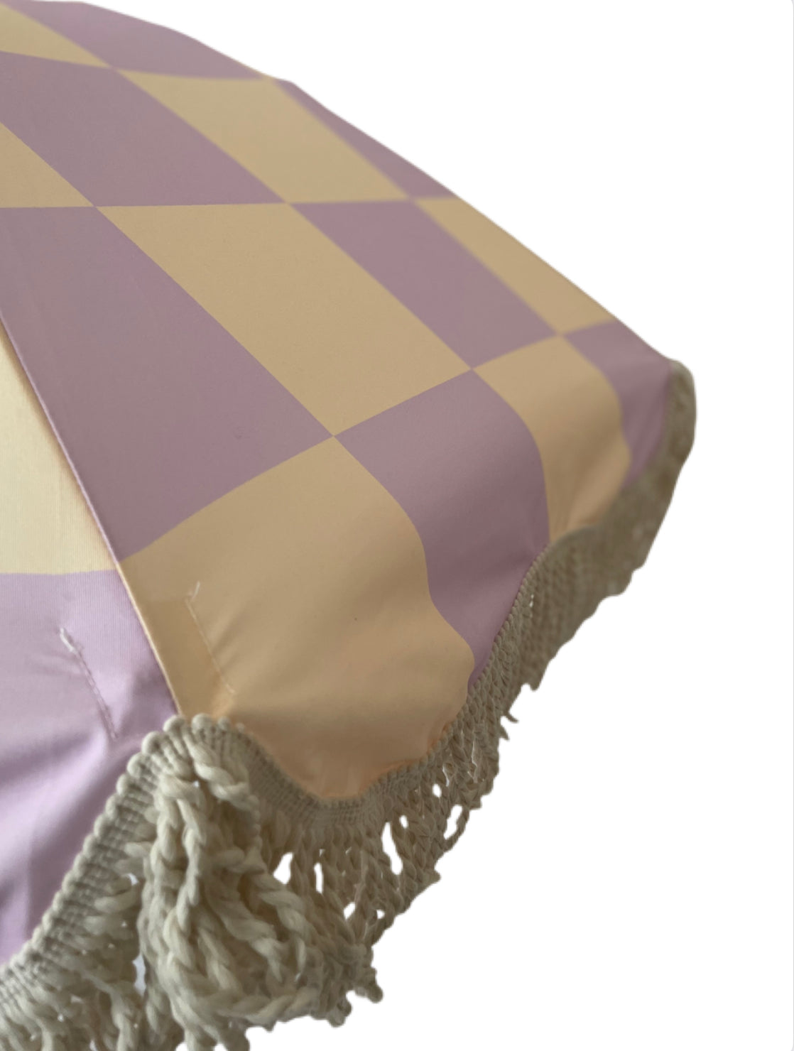 The Mabel boho chic parasol with lilac and cream checkerboard print, natural cotton fringing, adjustable wooden frame pole, collapsible design, and matching canvas carry bag.