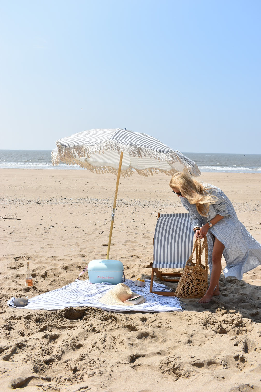 The Betty timeless chic parasol with natural cotton fringing, wooden frame pole, adjustable positioning, collapsible design, and matching canvas carry bag. Beach umbrella.