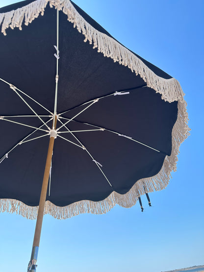 The Dorothy luxury black parasol with natural cotton fringing, wooden frame pole, adjustable positioning, collapsible design, signature logo panel, and matching carry bag.&quot;