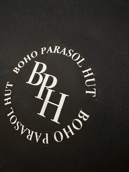The Dorothy luxury black parasol with natural cotton fringing, wooden frame pole, adjustable positioning, collapsible design, signature logo panel, and matching carry bag.&quot;