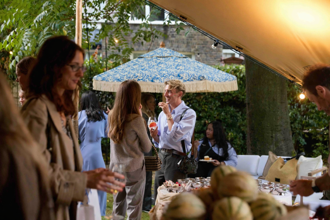 Blue multi-colour floral parasol in Liberty fabric with straight edge fringing at a garden party event