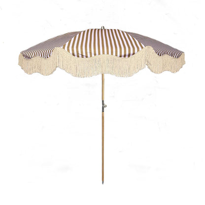 The Gigi luxury pink and camel striped parasol with natural cotton fringing, wooden frame pole, adjustable positioning, collapsible design, and matching carry bag.