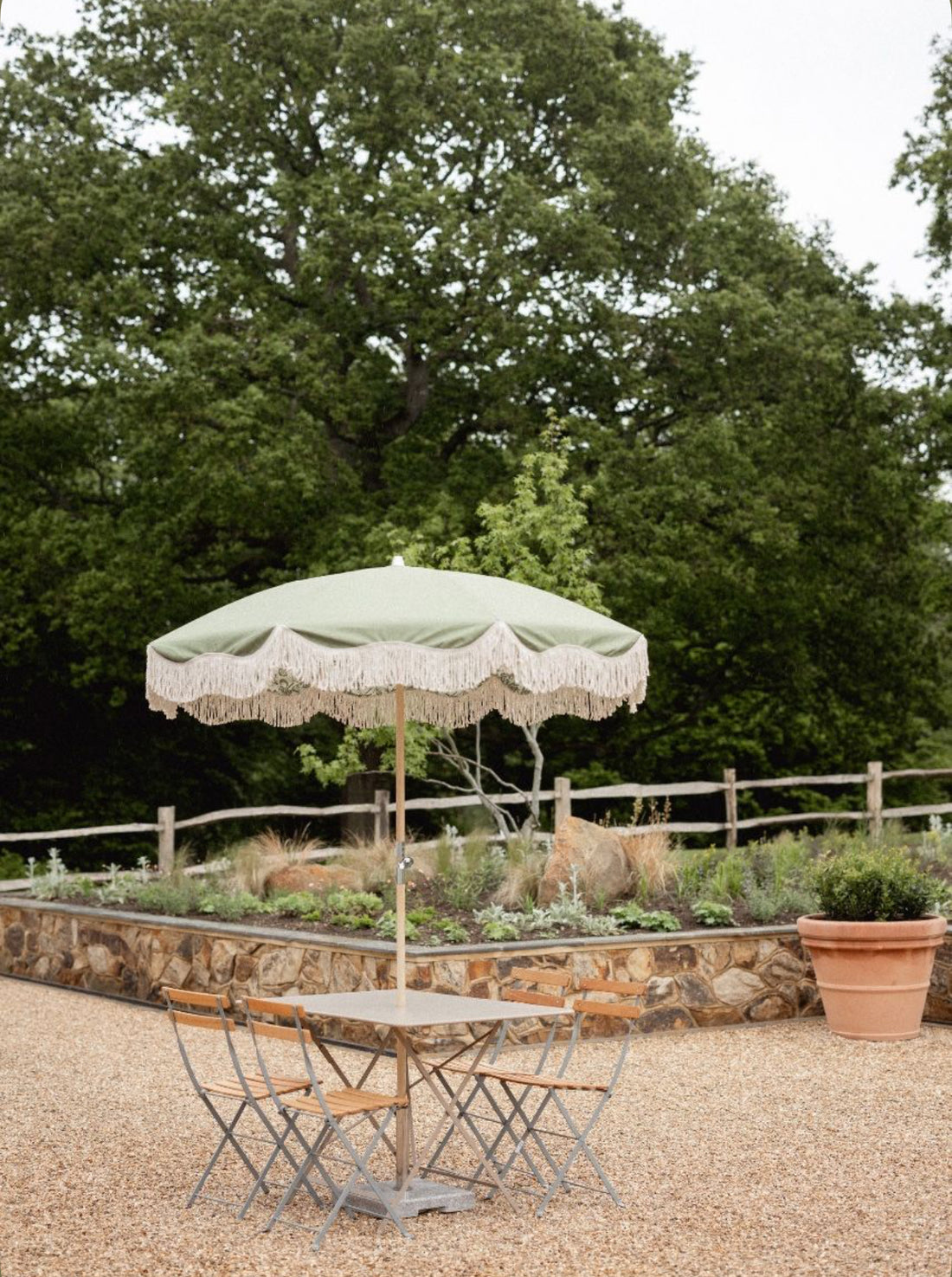 The Bridget olive green scalloped fringed garden parasol by Boho Parasol Hut over an outdoor dining table