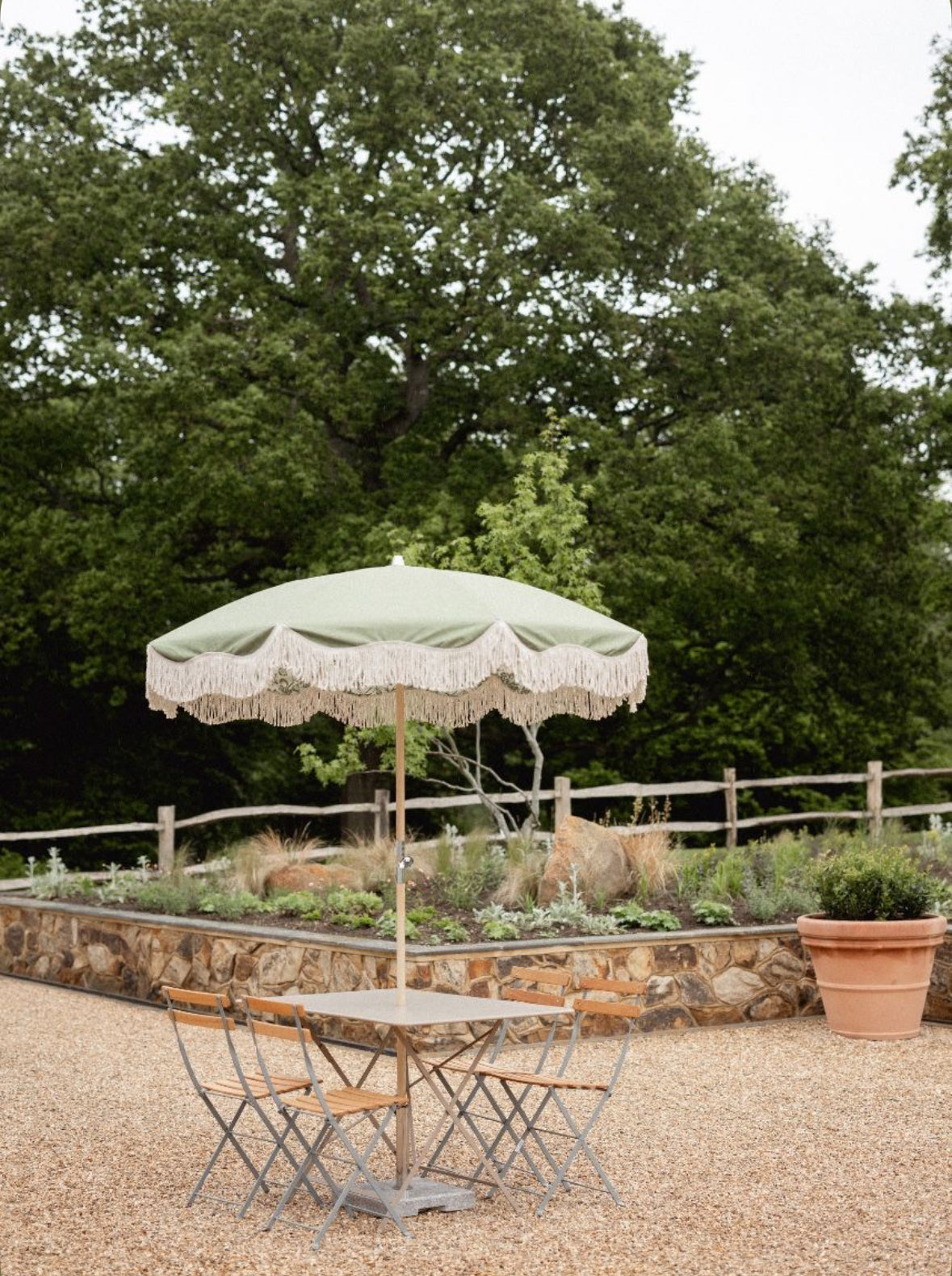 The Bridget olive green scalloped fringed garden parasol by Boho Parasol Hut over an outdoor dining table